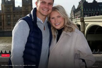 Katie Bates and Travis Clark smiling together in London with the Houses of Parliament behind them
