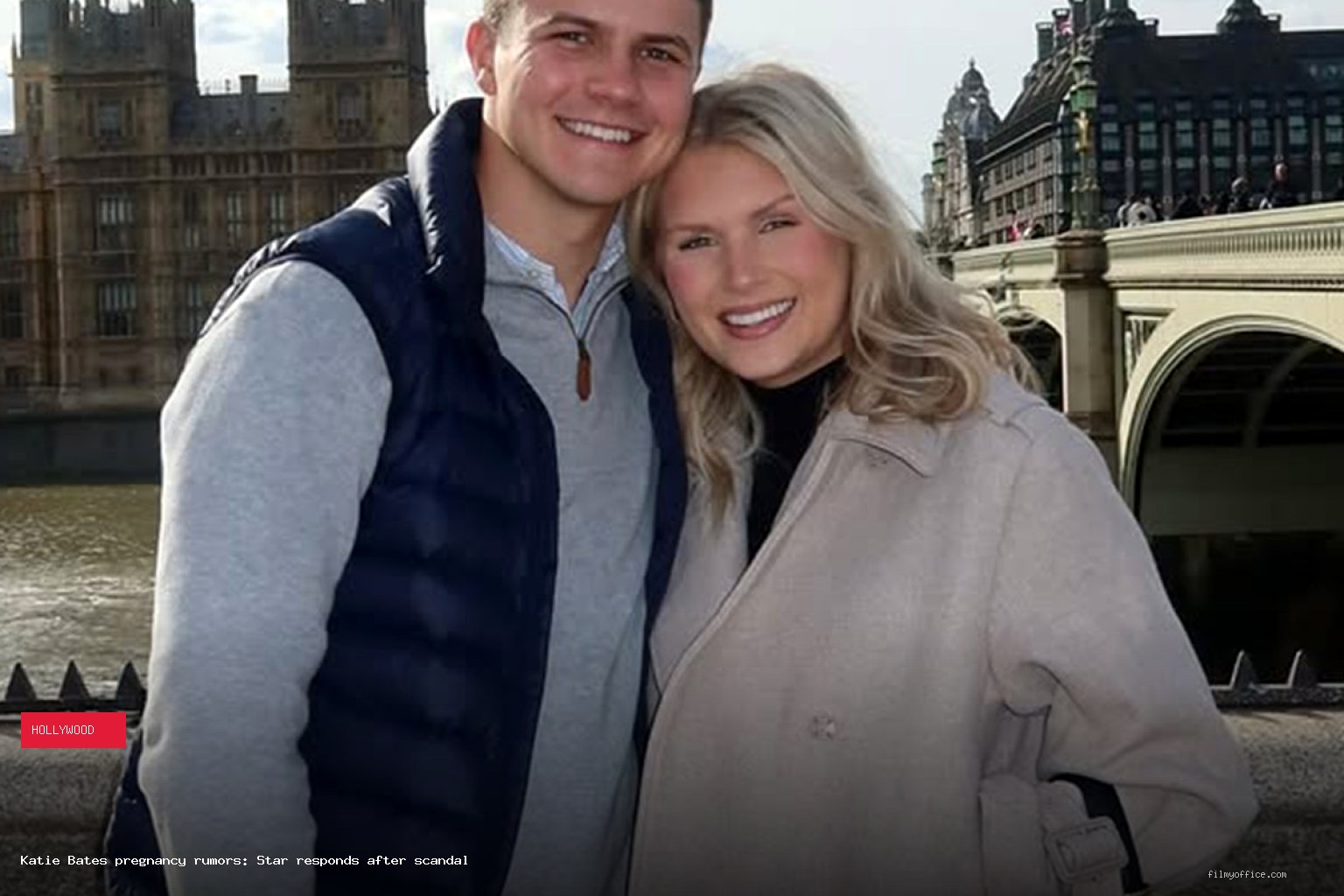 Katie Bates and Travis Clark smiling together in London with the Houses of Parliament behind them